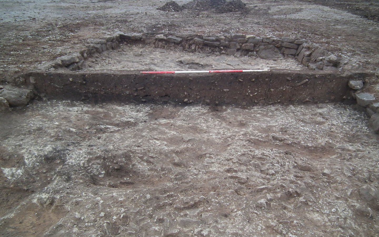 A large archaeological excavation exposing stone building foundations