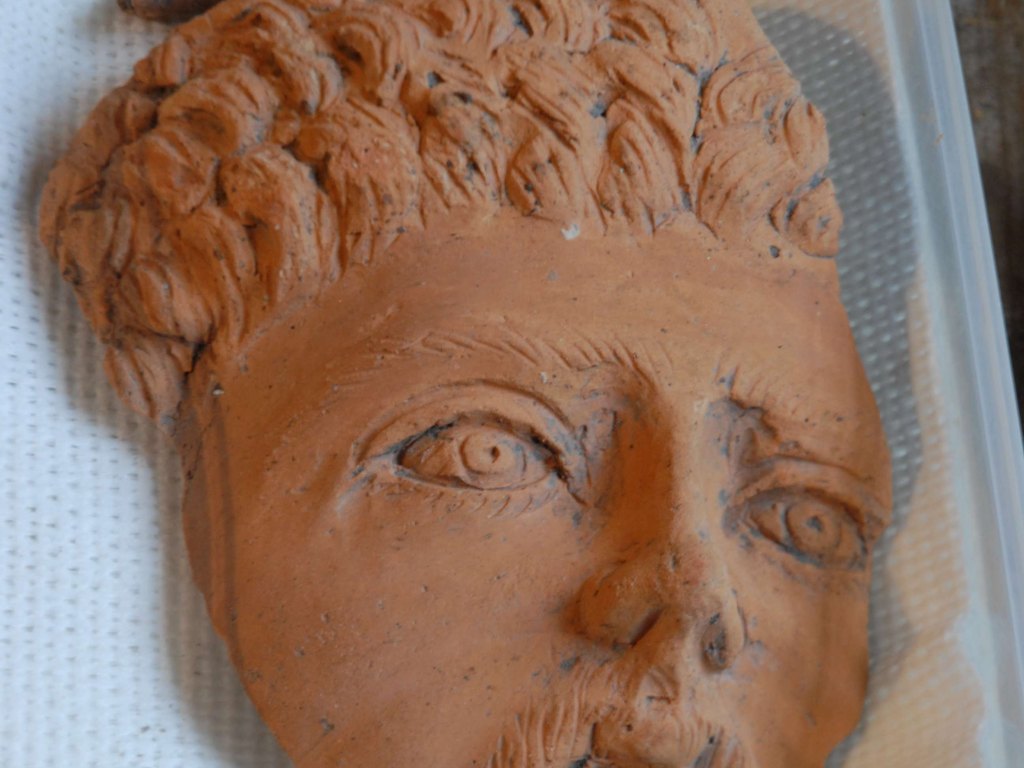 An archaeologist carefully cleaning and recording decorated pottery