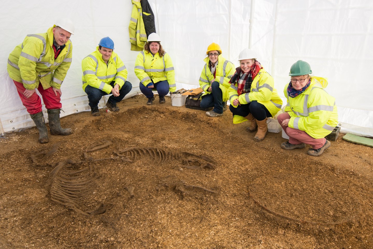 Archaeologist carefully recording a skeleton during excavation